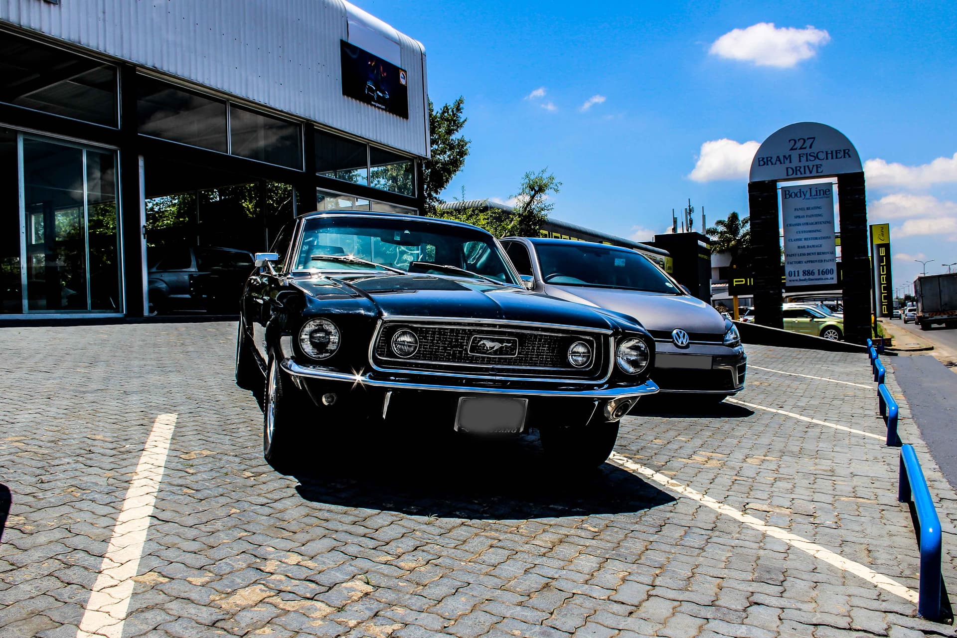 A Ford Mustang and VW Golf outside the workshop
